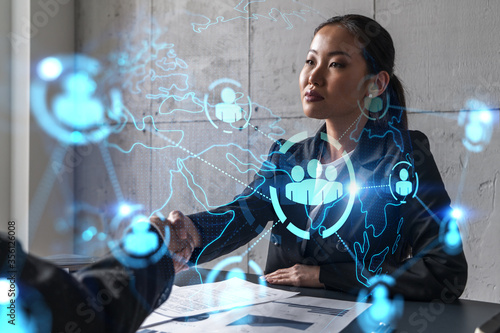 Two woman handshake. Social network hologram. Multiexposure. International business.