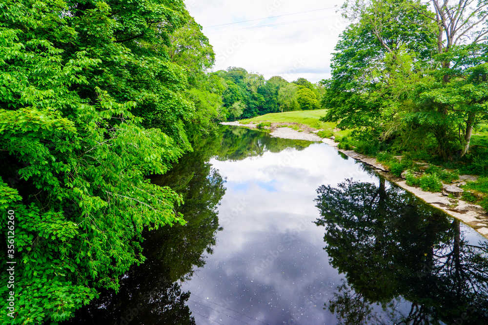 standing on a bridge looking down a slow moving river with green banks, summer. standing on a bridge looking down a slow moving river with green banks, summer.