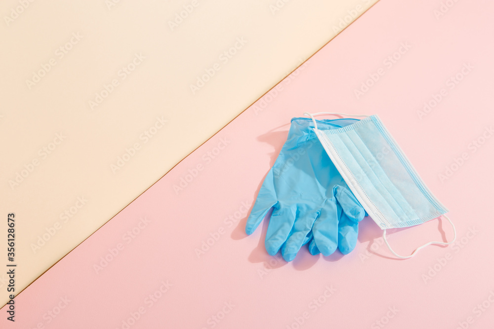 Blue medical gloves and mask on a yellow pink background. The concept of protection against disease. Copy space. Blue medical gloves and mask on a yellow pink background. The concept of protection against disease. Copy space.