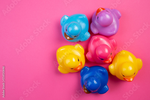rubber toy ducks of different colors on pink background