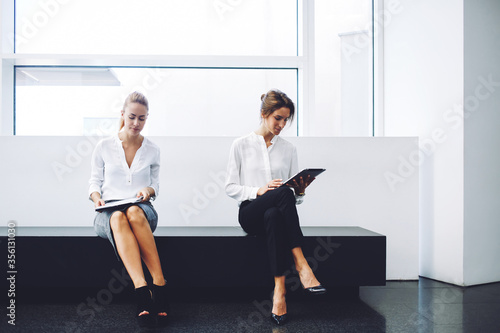 Canvas Print confident women entrepreneurs reading news by using digital tablet and cell tel