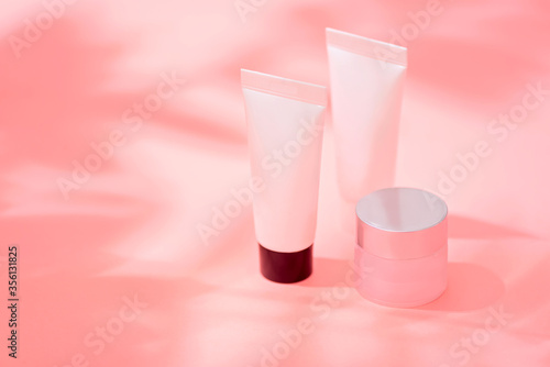 Cosmetics tube and jar over background with shadow