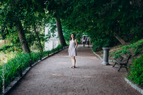 Sofia Park, Uman. Girl in a summer board on the alley of the park. Smiling brunette girl on a stone alley near the lake. Walk in the park, a large beautiful lake.