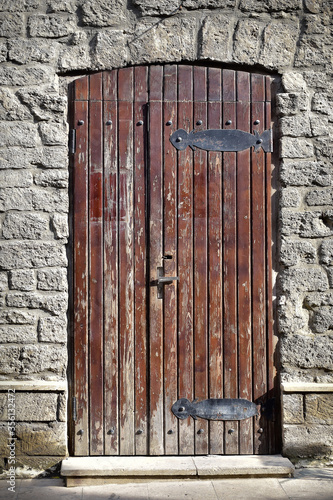 Atmospheric wooden door with shabby paint in the stone wall of the house