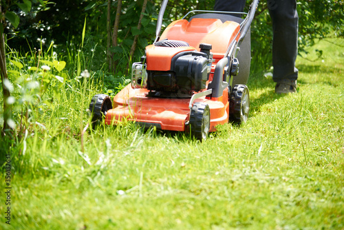 a close-up lawnmower mows the green grass on the lawn.Bright Sunny day