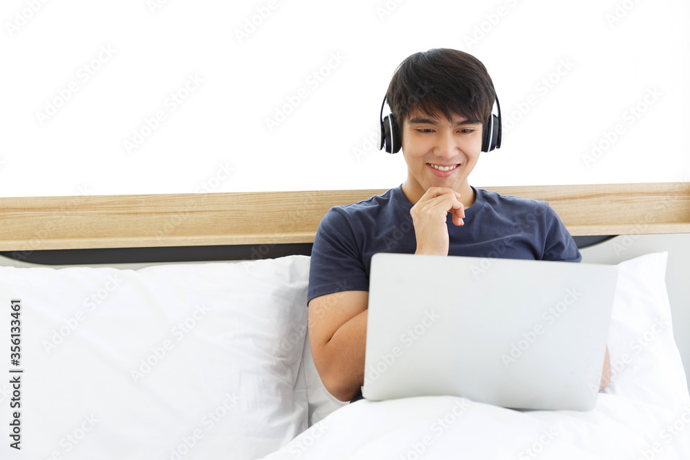 Happy man using Laptop computer and checking good News in the Bedroom. COPY SPACE. Trading. Watching Movie. WORK FROM HOME WFH Concept. Happy man using Laptop computer and checking good News in the Bedroom. COPY SPACE. Trading. Watching Movie. WORK FROM HOME WFH Concept.