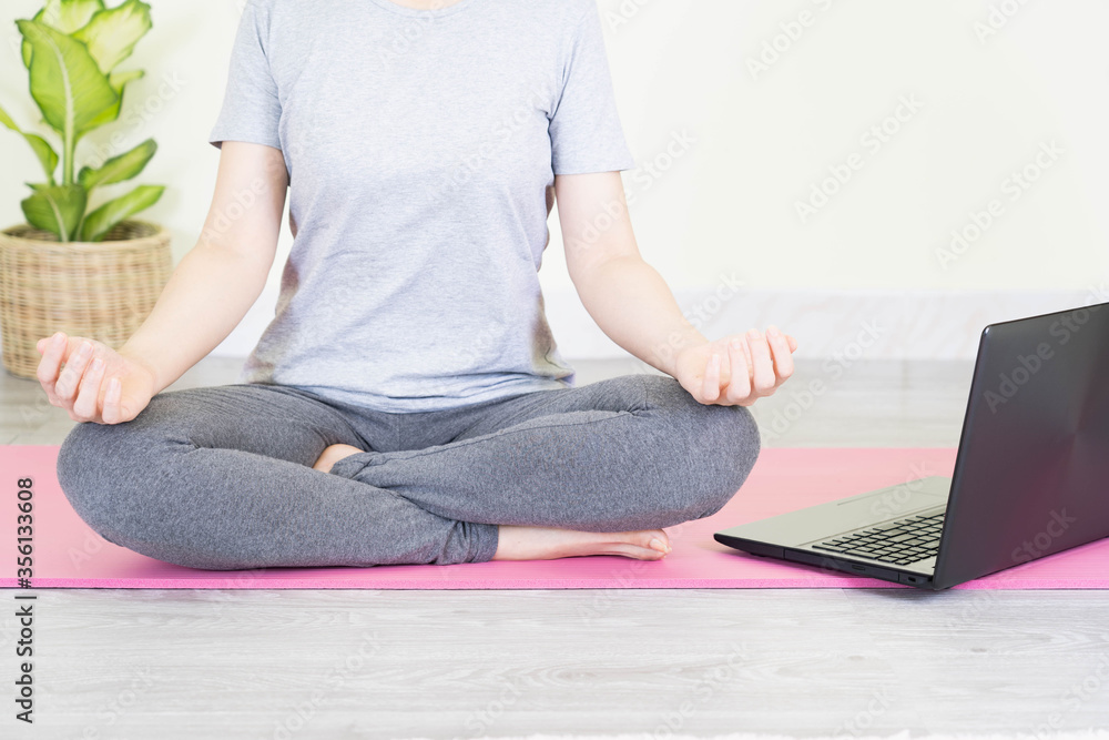 Naklejka premium Young beautiful asian woman doing training fitness workout sport exercise feel no stress free, using laptop while sitting on floor watches a yoga tutorial at screen at home on self