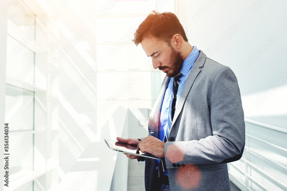 Happy intelligent man in suit talking on cell telephone and holding touch pad in the hand Happy intelligent man in suit talking on cell telephone and holding touch pad in the hand