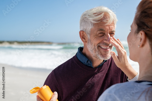 Bild auf Leinwand Woman applying sunscreen on senior man nose