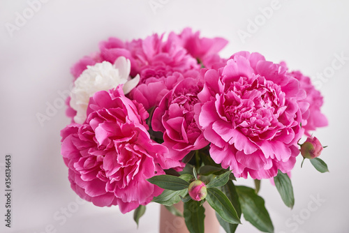 Fototapeta Naklejka Na Ścianę i Meble -  Peony bouquet in vase. Rich bunch of peonies. Greeting card for mother's day. Women's Day. Valentine's Day. Copy space. Spring or summer greeting card with flowers.Wedding invitation.Happy Birthday