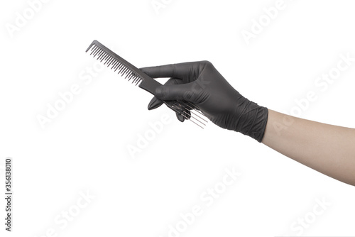 Hand in a black glove with a Barber's comb on a white background/ Hairdresser tools.