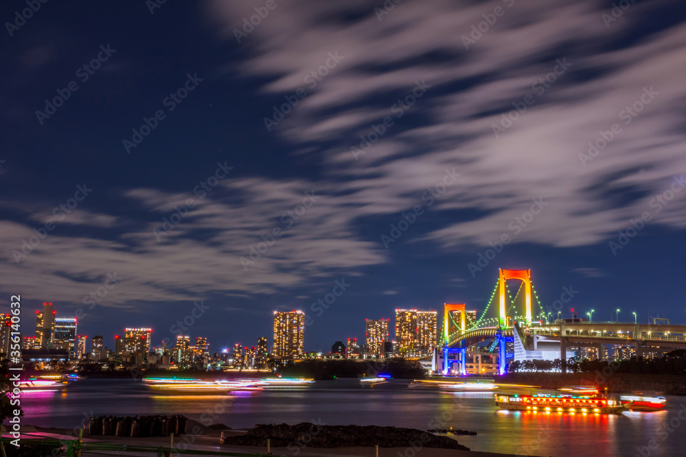 Obraz premium Odaiba, Tokyo, Beautiful and colorful rainbow bridge and Tokyo city night background image, cloudy in motion and left copy space for Title.