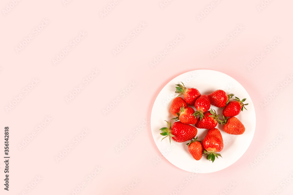 Top view strawberry in a white plate on a pink background. horizontal space for text Top view strawberry in a white plate on a pink background. horizontal space for text