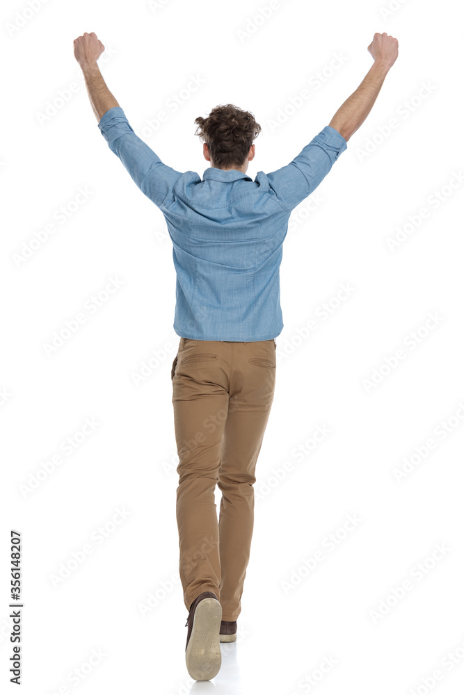 back view of enthusiastic guy holding arms in the air back view of enthusiastic guy holding arms in the air