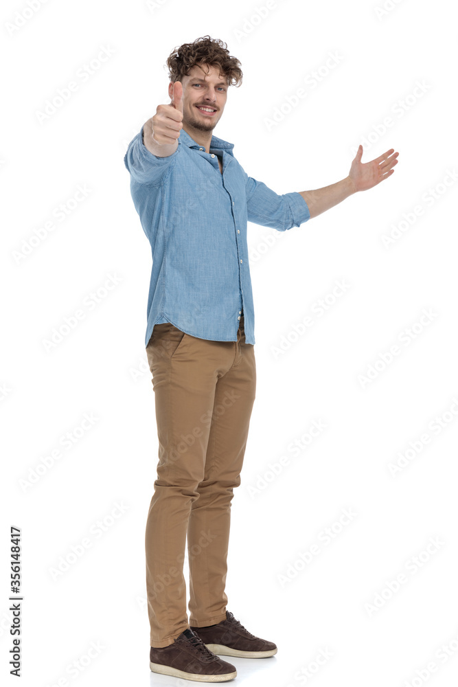 casual young man inviting to side and making thumbs up sign casual young man inviting to side and making thumbs up sign