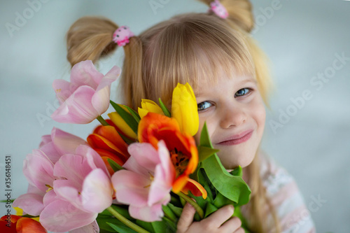 baby in pajamas with a bouquet of tulips