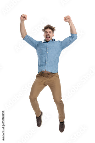 excited young casual guy in denim shirt jumping and celebrating