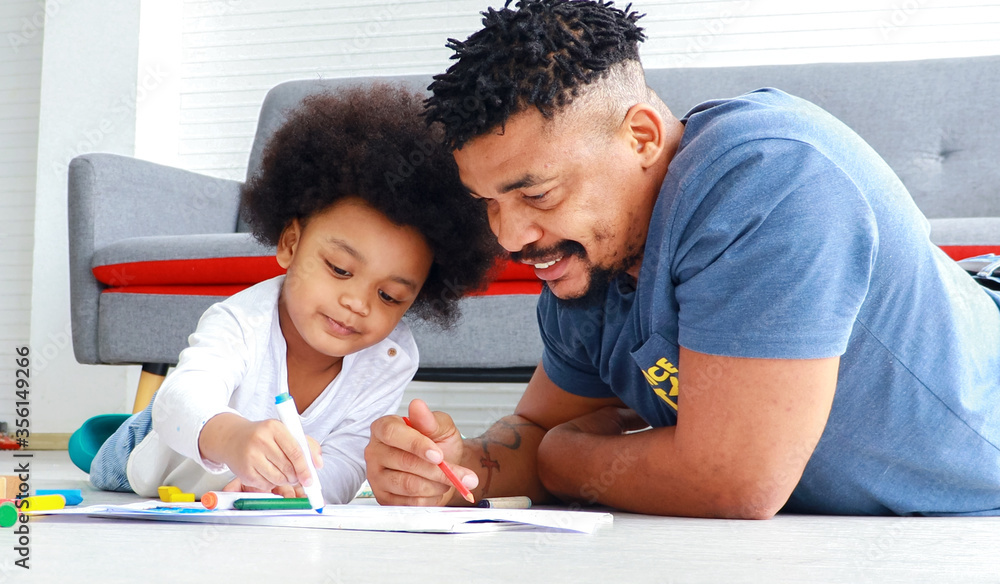 Happy African father and son are drawing and writing at home. Concepts of education and learning of children