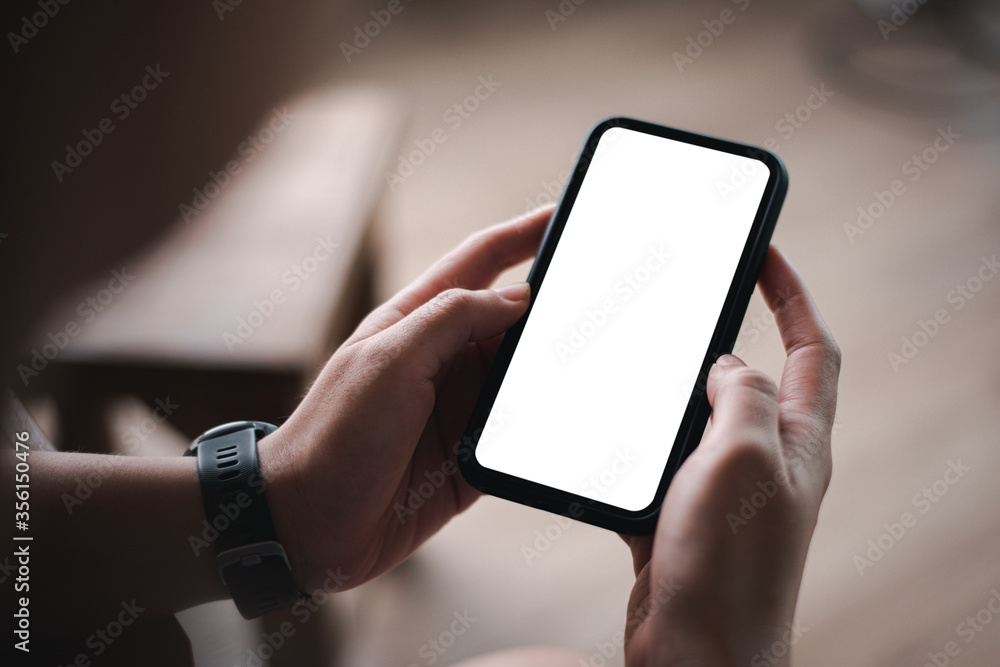 woman's hand holding black mobile phone with blank desktop screen. empty screen for mockup image or advertisement.