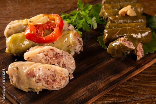 Arabic food. Appetizing cabbage rolls and Rice and mint wrapped in grape vine leaves on wood background photo