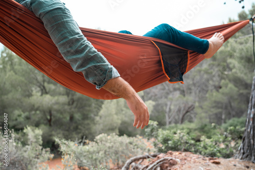 Fototapeta Naklejka Na Ścianę i Meble -  Man's arm hanging from a hammock hanging in a forest