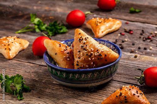 Uzbek national dish samosa. Indian samosas baked pastry with savoury filling, popular Indian snacks, served in bowl with spices on rustic background, top view photo