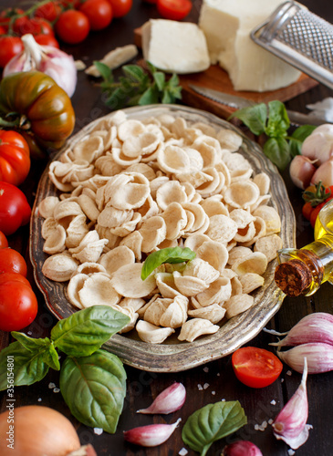 Fotografie Fresh raw  italian pasta orecchiette, vegetables, herbs and olive oil