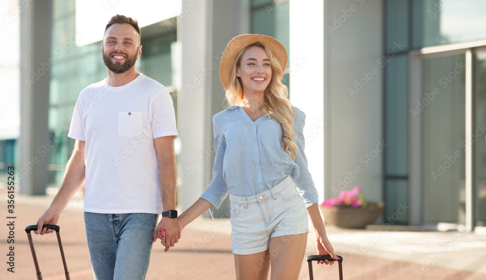 Happy couple walking in airport with baggage, copy space Happy couple walking in airport with baggage, copy space