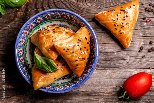 Uzbek and Central Asia cuisine concept. Samsa or Sambousak in national plate. Samsa or Sambousak an oriental meal to be stuffed with minced meat, cheese or vegetables photo