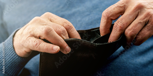 aged pensioner searches for money in empty black wallet