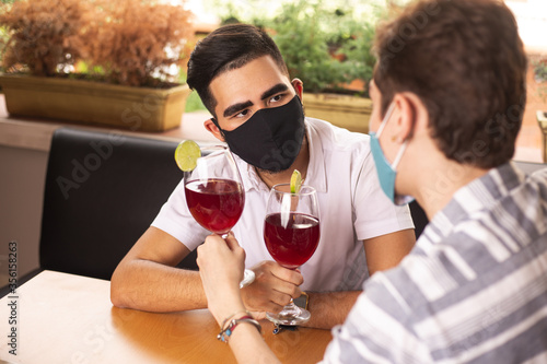 gay couple in restaurant wearing masks. social distancing, restaurants reopening