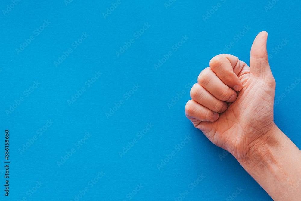 Hand making a like gesture against a blue background Hand making a like gesture against a blue background