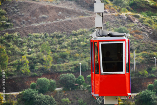 Red cable car that passes over the city of Zacatecas Mexico on the Cerro de la Bufa, with a green landscape and a hill in the background, a tourist place in Mexico.