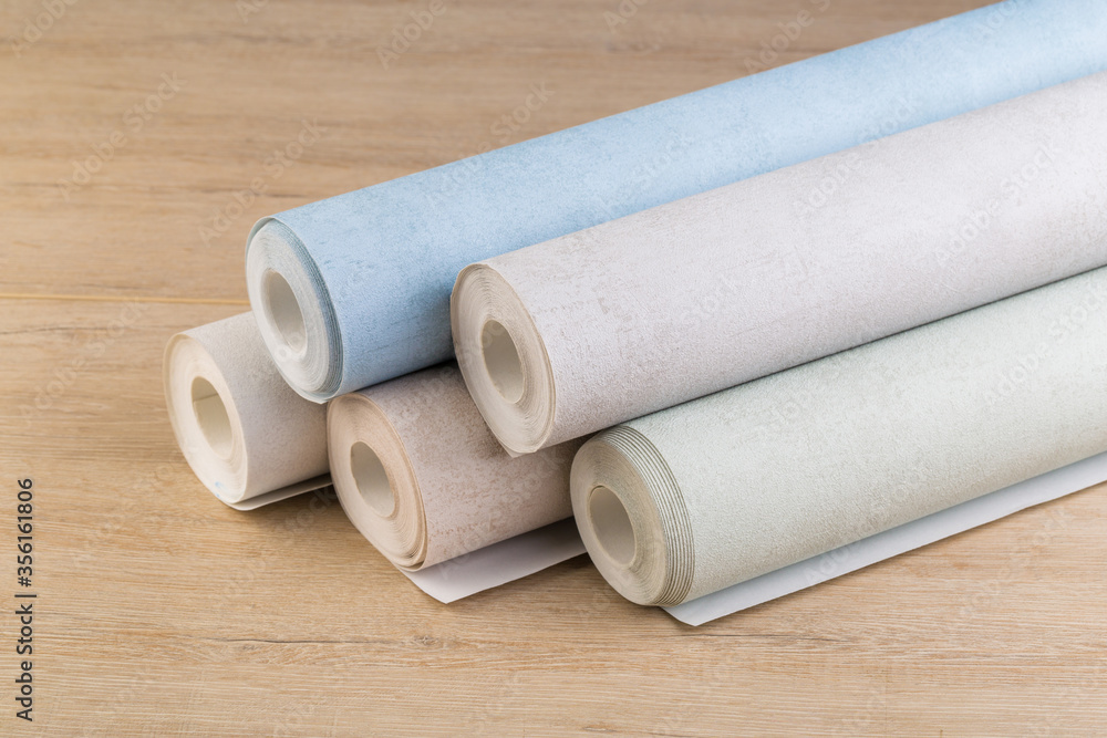 rolls of multi-colored paper wallpaper on a wooden table rolls of multi-colored paper wallpaper on a wooden table