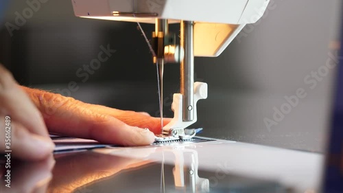Sewing machine needle stitching cotton fabric in slow motion. Woman hand sewing cloth face mask.