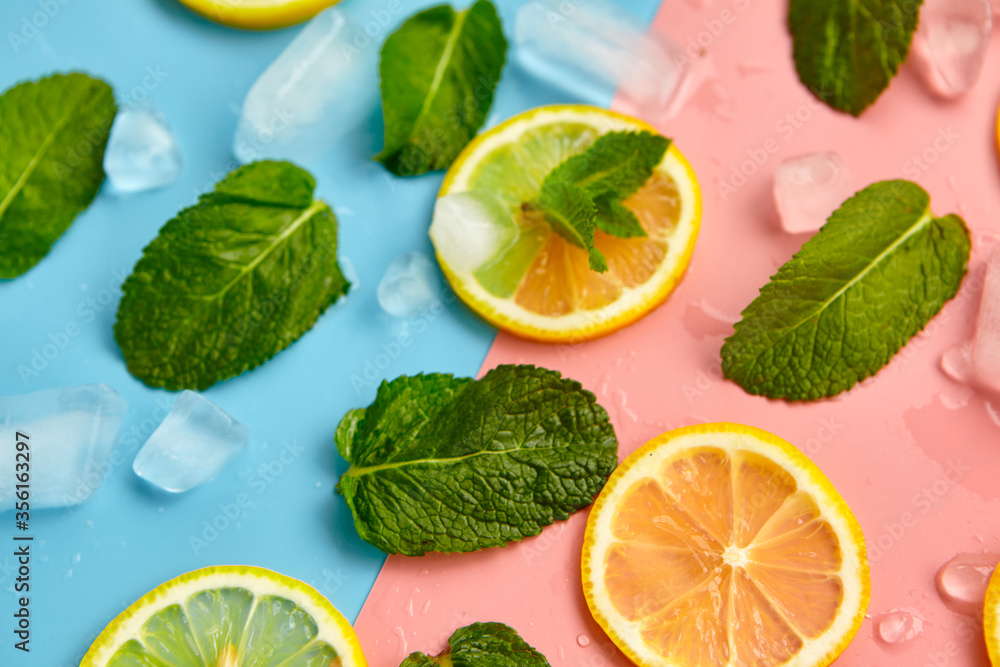 Composition with cut citrus fruits on color background. Creative summer background composition with lemon slices, leaves mint and ice cubes. Minimal top down lemonade drink concept.Top view Composition with cut citrus fruits on color background. Creative summer background composition with lemon slices, leaves mint and ice cubes. Minimal top down lemonade drink concept.Top view