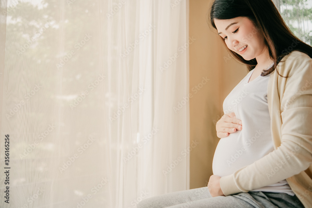 Beautiful woman Asia Happy Is pregnant in bed at home people and expectation concept Female pregnancy Hands holding belly Headphones for children Gray dress teens Will be a mother baby Beautiful woman Asia Happy Is pregnant in bed at home people and expectation concept Female pregnancy Hands holding belly Headphones for children Gray dress teens Will be a mother baby