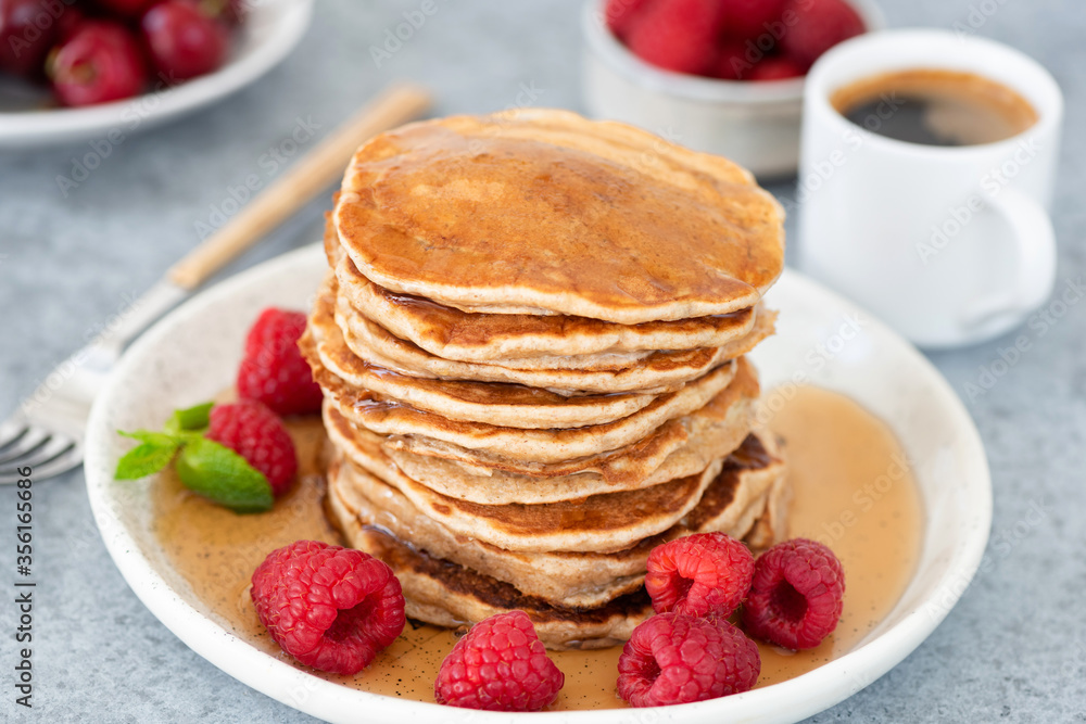 Pancakes with syrup and raspberries on plate, cup of espresso coffee on background. Tasty sweet breakfast food Pancakes with syrup and raspberries on plate, cup of espresso coffee on background. Tasty sweet breakfast food