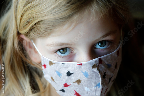 Kind Mädchen Gesicht mit Mundschutz, Gesichtsmaske aus Stoff als Schutz vor Corona photo