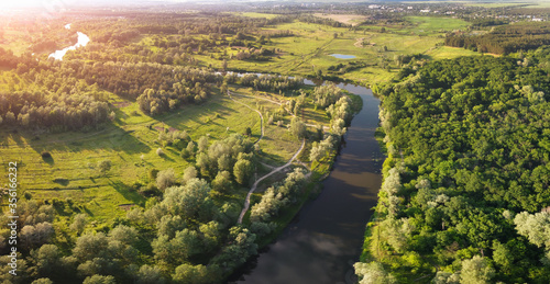 Evening aerial view on river bend with sunlight on horizon.