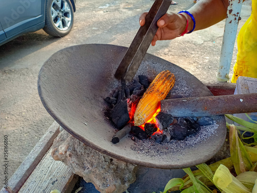 Indian Sweet corn being roasted on a traditional Charcoal fire at a street food cart in Mysuru city of Karnataka / India.