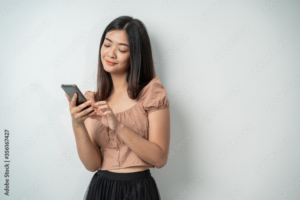 Beautiful girl uses a smartphone gadget and touches the screen with an isolated background Beautiful girl uses a smartphone gadget and touches the screen with an isolated background