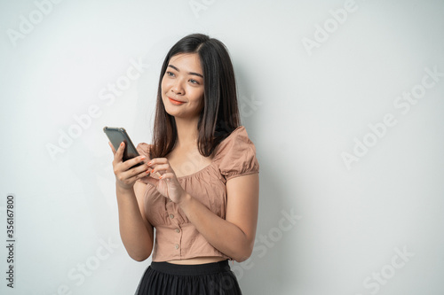 Beautiful girls smile when using smart phone gadgets and touching the screen with an isolated background