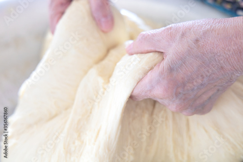 Kneading the dough in home. .Hands of an elderly woman knead the dough in her home.