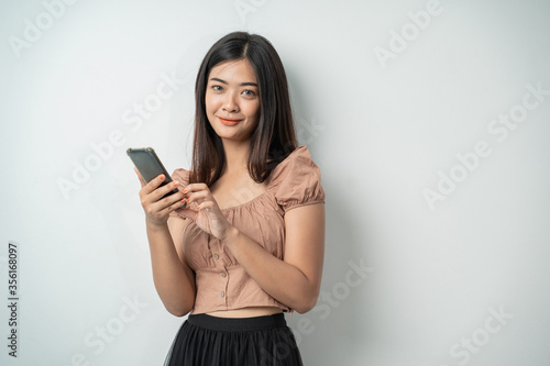 pretty girls look at the camera when using a smart phone gadget and touch the screen with an isolated background