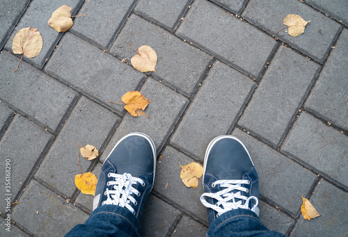 Sneakers on the background of autumn road tiles