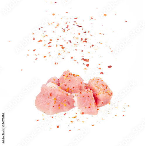 Sliced raw meat pork sprinkled with seasoning on a white background