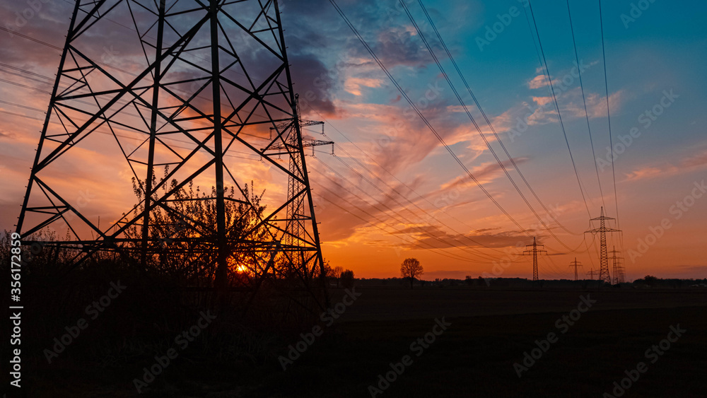 Beautiful sunset with dramatic clouds and powerlines near Tabertshausen, Bavaria, Germany