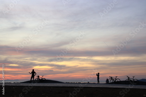 Silhouette of a cyclist on the beach at sunrise.
