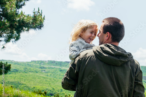 Joyful dad and daughter are playing outdoors in the park. The concept of a happy family. Dad with a baby.